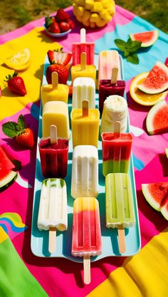 popsicles and watermelon are arranged on a colorful tablecloth with fruit in the background