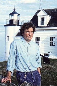 a man standing in front of a white lighthouse