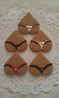 four decorated rocks sitting on top of a white doily with lace around the edges