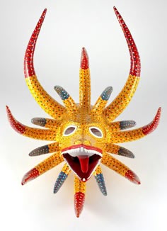 a yellow mask with an open mouth on a white background and red, green, blue, and yellow colors