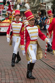two men in red and gold uniforms marching down the street
