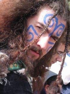 a man with his face painted in blue and white is looking down at the ground