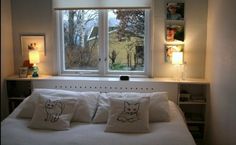 a bed with white sheets and pillows in front of a window that has pictures on it
