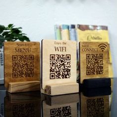 three wooden blocks with qr code designs on them sitting on a table next to a potted plant