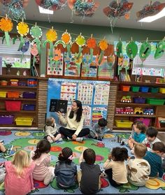 a group of children sitting on the floor in front of a teacher