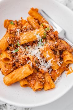 a white plate topped with pasta covered in sauce and parmesan sprinkles