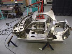 a car frame is being worked on in a garage with other tools and equipment around it