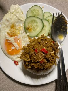 a white plate topped with eggs, cucumbers and other food on top of it