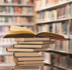 a stack of books sitting on top of each other in front of a book shelf