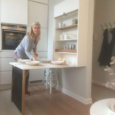a woman standing in front of a table with plates on it and candles burning behind her