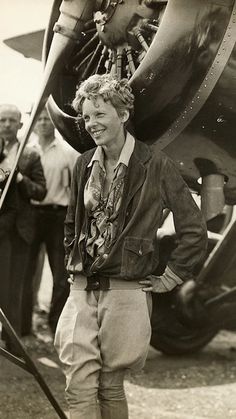 an old black and white photo of a man standing in front of a plane with his hands on his hips