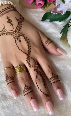 henna tattoo on the hand of a woman with pink flowers in the back ground