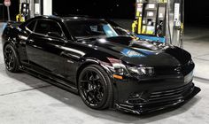 a black sports car is parked at a gas station