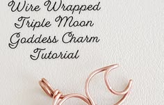 the wire wrapped triple moon goddess charm is laying on top of a piece of paper