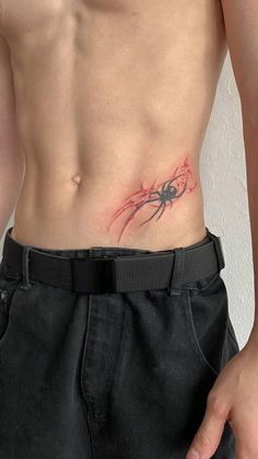 a man with a spider tattoo on his stomach and chest is standing in front of a white wall