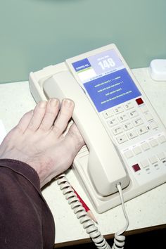 a person using an old style telephone on a desk with a clock in the background