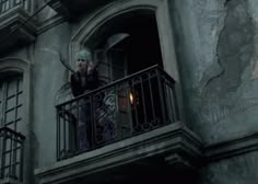 a woman standing on top of a balcony next to a building