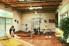 three people sitting on the floor in a room with wooden floors and ceilings, while one person sits on a bench