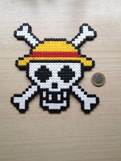 a piece of bead art with a skull wearing a hat and crossbones