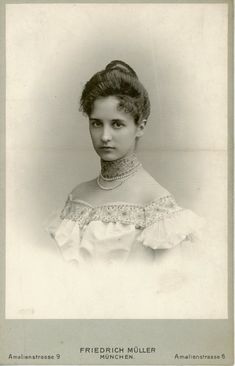 an old black and white photo of a woman with necklaces on her neck, looking at the camera
