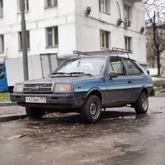 an old car is parked on the side of the road in front of a building