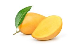 two mangos with one cut in half and green leaf on the top, against a white background