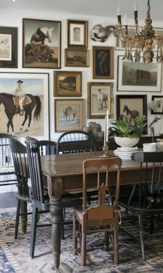 a dining room table with chairs and pictures on the wall behind it, including a horse