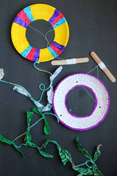 two paper plates and some crafting supplies on a black surface with scissors, yarn, and glue