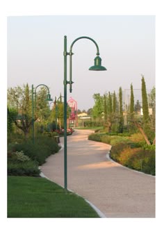 a street light sitting on the side of a road next to a lush green park