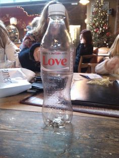 a bottle of love water sitting on top of a wooden table next to other people