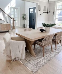 a dining room table with chairs and a rug on the floor in front of it