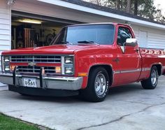a red truck parked in front of a garage