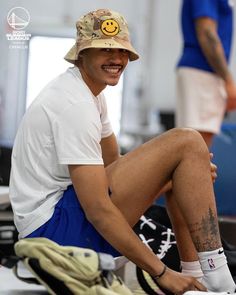 a man sitting on the ground wearing a hat and socks with his feet up in front of him