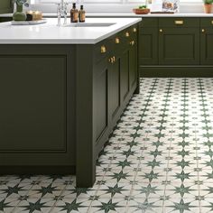 a kitchen with green cabinets and white counter tops, along with an ornate tiled floor
