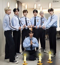 a group of young men standing next to each other with candles in front of them