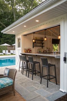 an outdoor bar with stools next to a pool