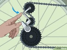 a hand is pulling the chain off of a bicycle wheel with a pair of scissors
