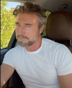 a man sitting in the back seat of a car wearing a white t - shirt