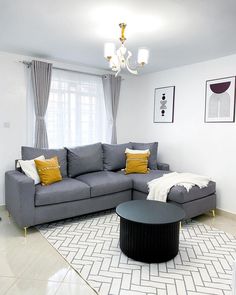 a living room filled with furniture and a chandelier hanging from the ceiling above it