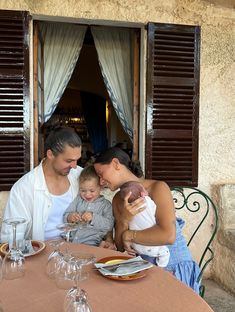 a man, woman and child sitting at a table with wine glasses on the table