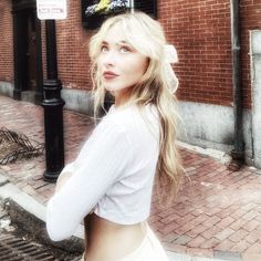 a woman is standing on the sidewalk in front of a brick building