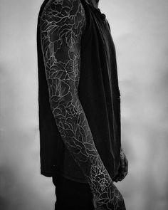 black and white photograph of a man with tattoos on his arm, looking to the side