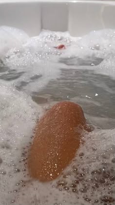 an orange ball floating in the water next to some foamy bubbles on top of it