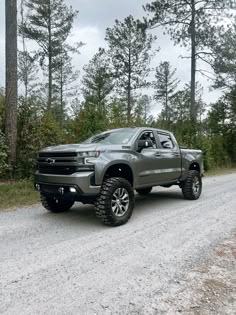 a silver truck parked on the side of a dirt road