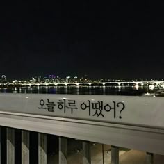 a sign that is written on the side of a building near water and city lights