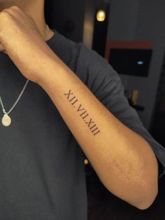 a man is holding his arm with roman numerals tattooed on the side of his arm