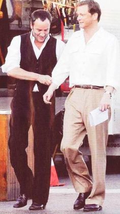 two men standing next to each other in front of a truck