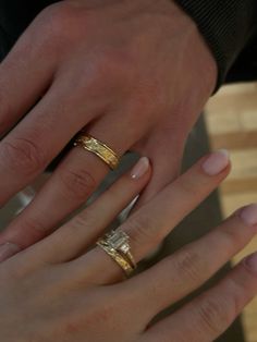 two people with wedding rings on their hands, one holding the other's hand