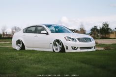 a white car parked on top of a lush green field