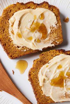 two pieces of bread on a plate with peanut butter and jelly spread on top, next to a wooden spoon